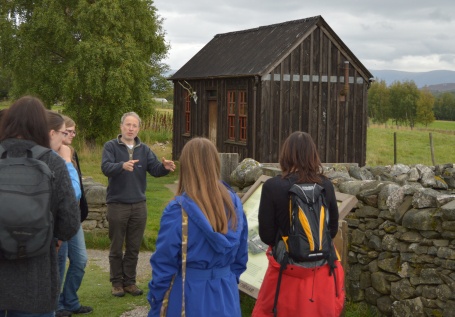 Teacher and students in front of a wooden structure in Newtonmore.