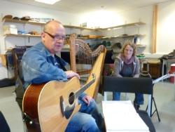 Man with guitar in foreground and woman with harp in background