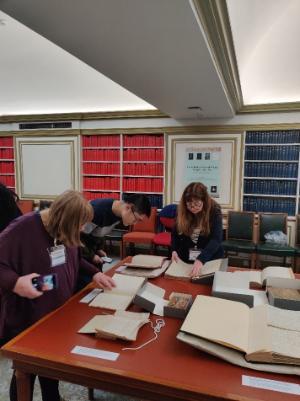 Three people reading documents at the National Library