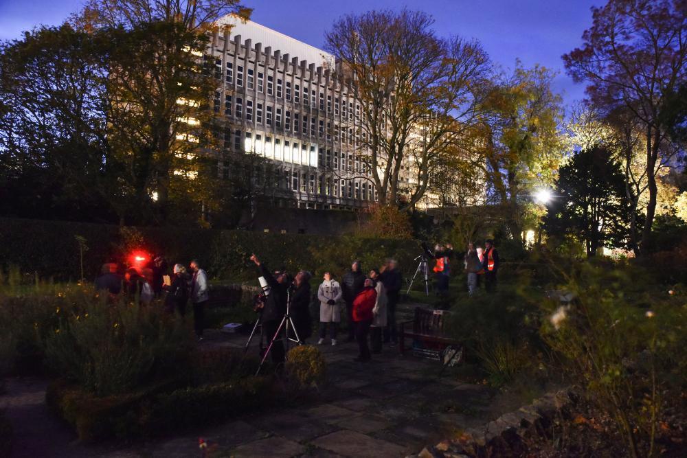 Stargazing in the Rose Garden. Several telescopes are set up and astronomers are describing to 10-15 guests how they work and what they can see.