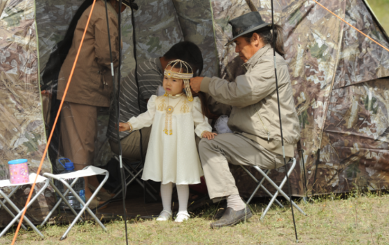 A relative helps a little girl with her Sakha national costume. Photo courtesy of Maksim Unarov