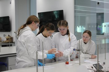 A group of school students in lab coats working together on an experiment