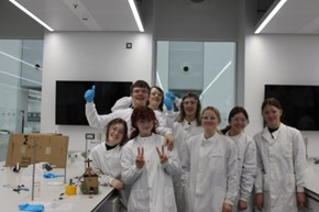 A group of school students in lab coats smiling at the camera