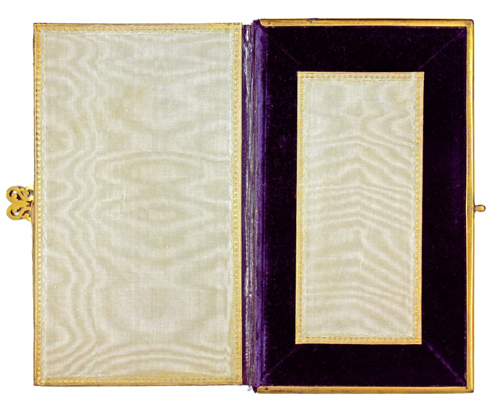 An open book with gold edging around the edges of the book. The opening page is dark purple with a cream insert.