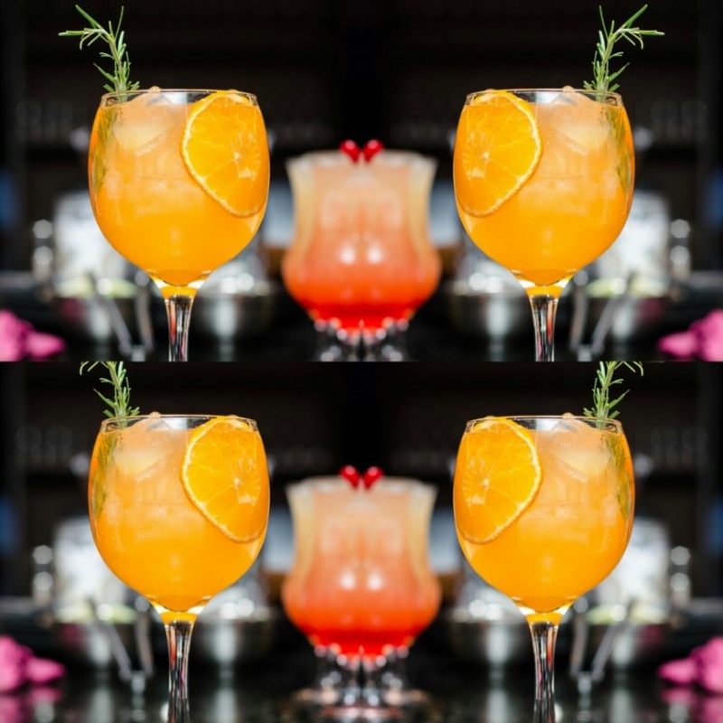 Orange cocktail in a glass with a sprig of rosemary garnish