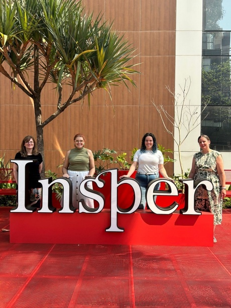 Left to right: Sharon Gordon, Luciana de Paula Arjona, Jucilene Lopes and Katie Wilde standing behind the Insper sign outside an Insper university building.