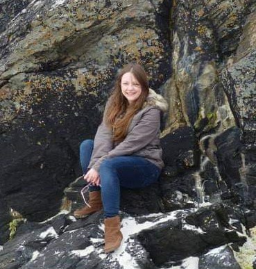 Picture of Sophie sitting on a rock at the beach.