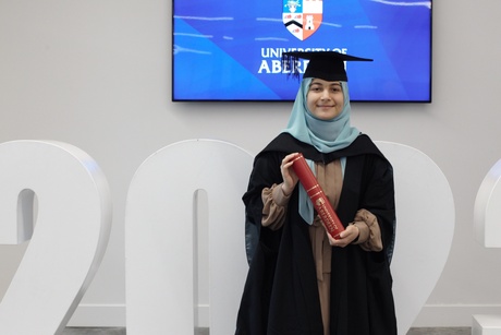 Blog Author in graduation gown with scroll