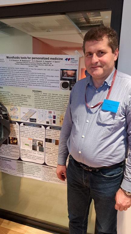 Dr Claudiu Giuraniuc standing in front of his poster at the 9th NHS Grampian Research Conference - Mind the Gap event on 4-5 October 2024