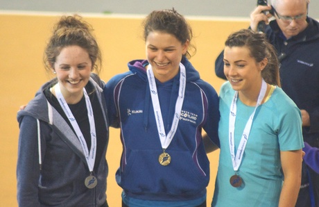 Zoey Clark (centre) celebrates a gold medal win at the Scottish Senior Indoor Championships | Credit: Eddie McKenna