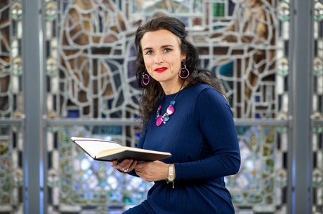 A person holding a book in front of a stained glass window