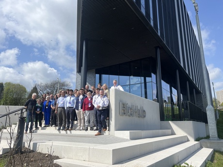 The group of participants tanding on the steps outside a large glass bulding