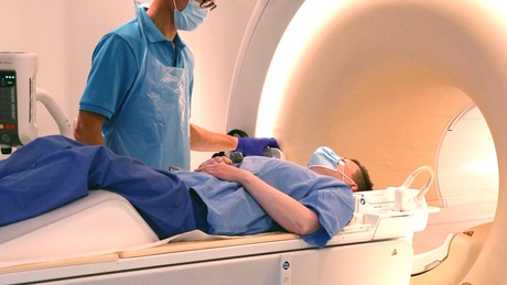 A radiographer oversees a patient as they enter an MRI scanner
