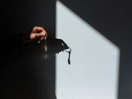 A hand holding keys with the silhouette cast on a wall