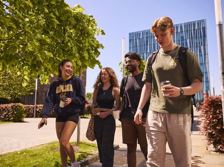 A group of four students walking and laughing on campus at Old Aberdeen