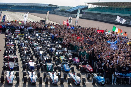 A huge group of all the students involved and their cars on the race track