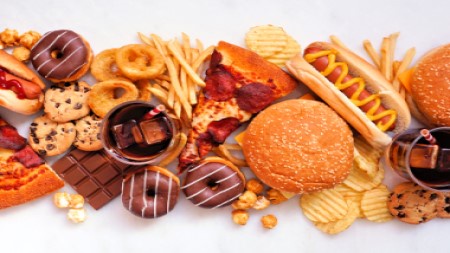 image shows a range of unhealthy foods including donuts, hotdogs, pizza and chips
