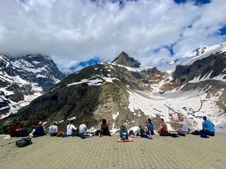 People sitting in a row in front of a mountain range
