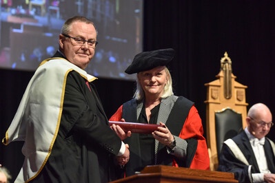 Honorary graduate Jake Molloy receiving his scroll on stage