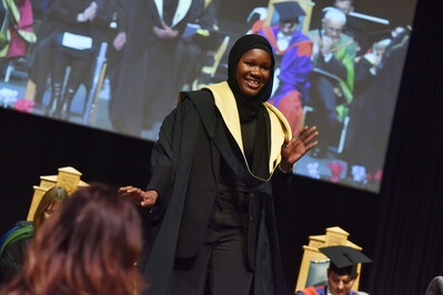 A woman waving as she walks off stage