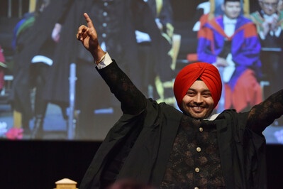 A person walking off the graduation stage with his hands in the air