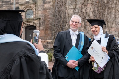 Two people smiling as their photo is taken on a phone