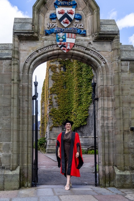 Monica ostic standing under an arch near the New King's Building