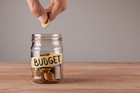 A jar of coins with a sticker saying 'budget' taped to it