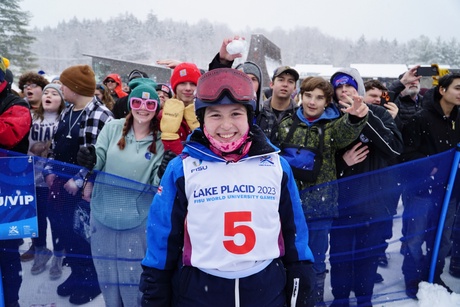 A photo of skier, Olivia Burke, with a crowd of people behind her on a snowy day