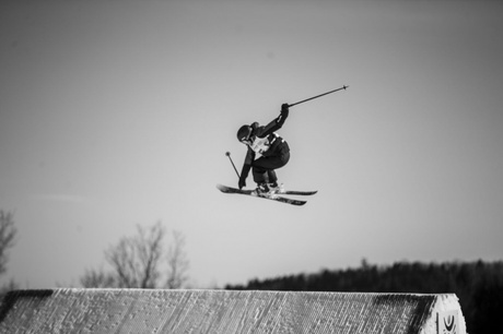 A black and white photograph of a skier in the air with a snowy landscape in the background