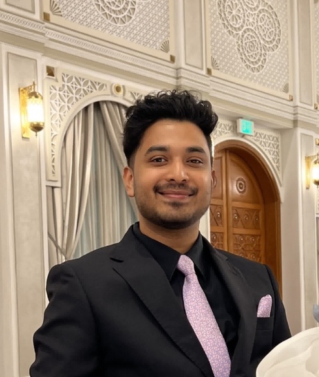 A headshot of a student smiling who is dressed in a suit