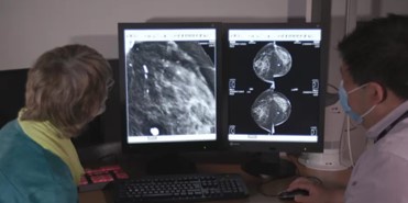 A patient and doctor looking at breast screening images on a computer.