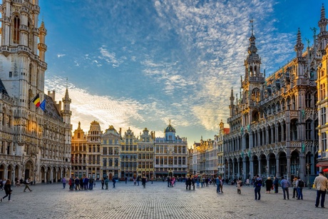 sunny square surrounded by large old buildings and palaces, with cobble stone and tourists.