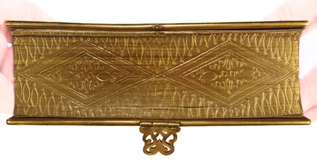 The edge of a book is shown, painted gold with fine geometric detailing decorating the paper edge.