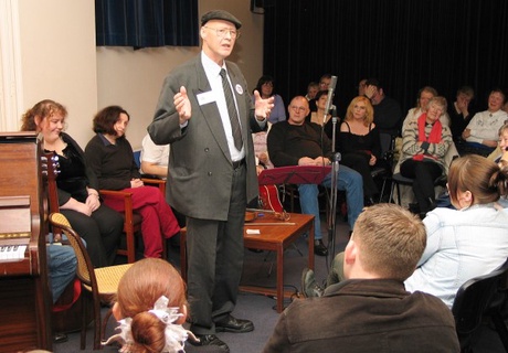 Man talking to seated audience sitting around him