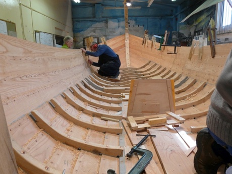 Boatbuilders working on planks of boat