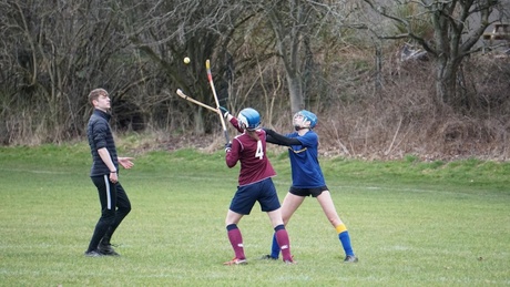 Two players vie for the ball in the air as a referee looks on