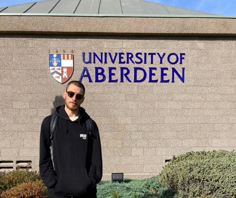 Frank in front of a University of Aberdeen sign