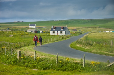 Two people walking down a country road in a rural setting.