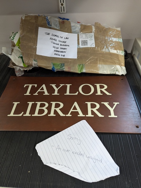 Image shows an open parcel, a library sign and a piece of paper with writing on it