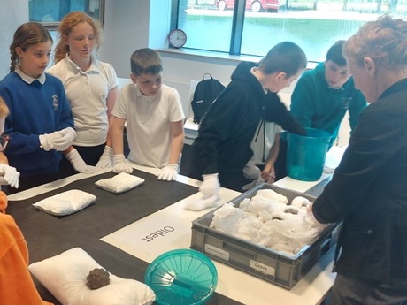 A small group of students examining objects laid out on a table