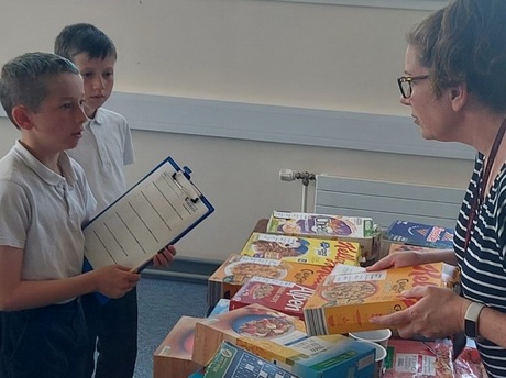 A small group of pupils being shown a range of breakfast cereal boxes