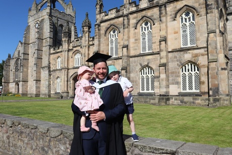 David standing in front of the chapel with two children