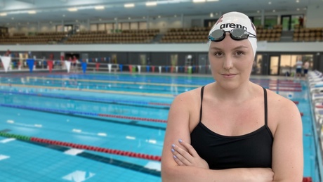 Faye in a swimming cap standing in front of the pool at ASV