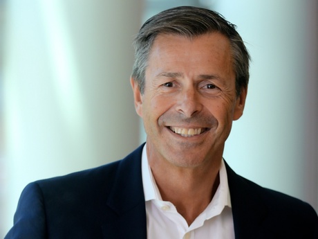 Head and shoulders image of a smiling Mark in a white suit and dark suit jacket