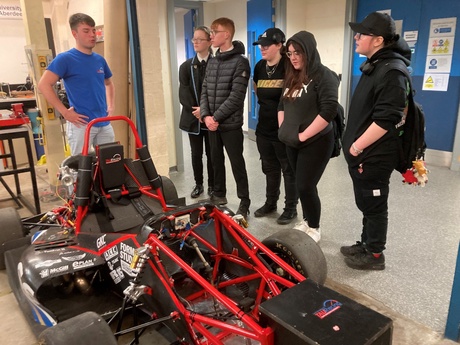 A group of senior students from Mintlaw Academy looking at the TAU racing car