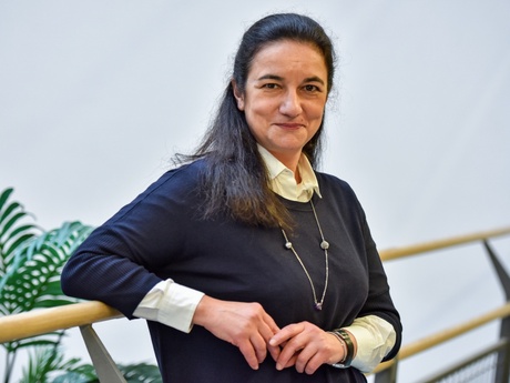 A smiling Miriam leaning against a balcony