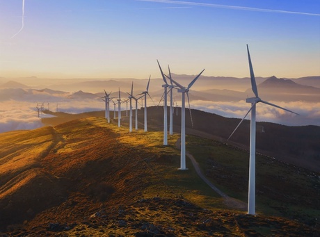 A line of wind turbines on a hilltop at sunset