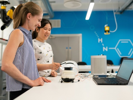 A female engineer demonstrates electornics to a younger female in a lab setting