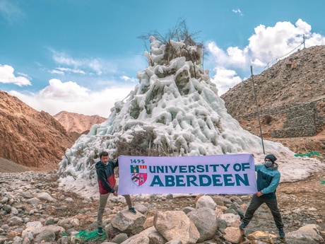 An ice stupa in Ladakh, India with a University of Aberdeen banner held up